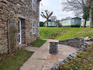 a stone house with a stone wall next to a sidewalk at Holiday Cottage 6 in Watermillock