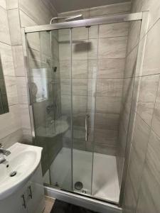 a shower with a glass door next to a sink at Whole Flat Close To Wembley in Wealdstone