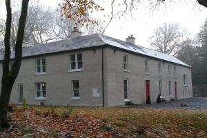 ein großes weißes Haus mit einer roten Tür in der Unterkunft Wood House Lodge in Tipperary