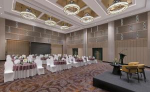 um salão de banquetes com mesas e cadeiras e um pódio em Grand Mercure Agra - An Accor Brand em Agra