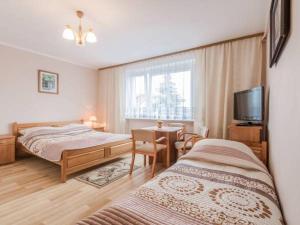 a bedroom with two beds and a table and a television at Willa Muszelka Przy Morzu in Jastarnia