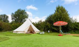 a large tent with a red umbrella in the grass at Spring Lakes lake view bell tents in Nottingham