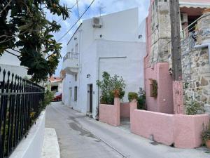 a narrow street with a white building and pink at Tsachaki Apartment Pigi Rethymno in Pigi