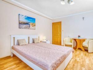 a white bedroom with a large bed and a table at Willa Muszelka Przy Morzu in Jastarnia