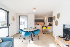 a living room with a table and blue chairs at Appartement neuf Côte de Granit Rose - Ploumanac'h in Perros-Guirec