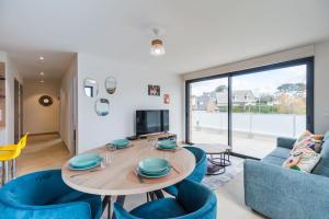 a living room with a table and blue chairs at Appartement neuf Côte de Granit Rose - Ploumanac'h in Perros-Guirec