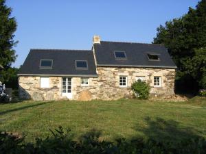 a stone house with a black roof on a field at Menez Triaou - Maison avec grand jardin in Plomodiern
