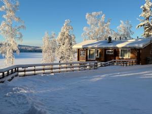 una cabaña de madera en la nieve con una valla en Villa Kägöne, en Parikkala 6 fotos más