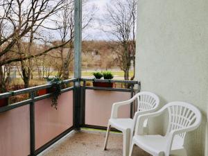 Duas cadeiras brancas sentadas numa varanda com uma janela em Apartment mit Wasserblick em Bernburg