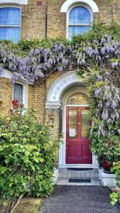 una puerta roja de una casa de ladrillo con flores púrpuras en St James's House en Londres