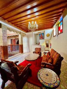 una sala de estar con muebles de cuero y una lámpara de araña. en Riad el wazania en Rabat
