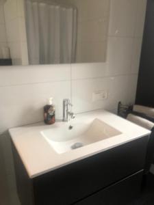 een witte wastafel in een badkamer met een spiegel bij City Zen Apartment Enschede !Free Private Parking in Enschede
