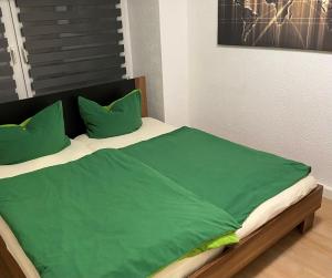 a bed with green sheets and pillows in a room at Haus Heiken in Altenburg