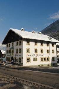 un grand bâtiment blanc sur le côté d'une rue dans l'établissement Gasthof Hirschen, à Kappl