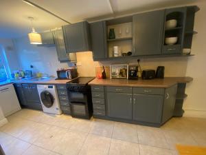 a kitchen with blue cabinets and a washer and dryer at Newly Furnished 5 Bedroom Gem in Sligo in Sligo