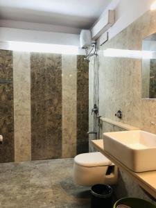 La salle de bains est pourvue de toilettes blanches et d'un lavabo. dans l'établissement WOODS - Mangalyam Meadows, à Valsād