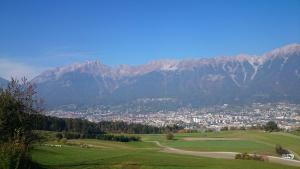 a green field with a city and mountains in the background at Appartements Wessely am Golfplatz Lans Innsbruck in Innsbruck