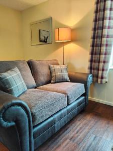 a living room with a couch and a lamp at Holiday Cottage 7 in Watermillock