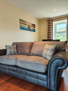 a brown couch in a living room with a window at Holiday Cottage 7 in Watermillock