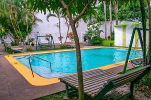 una piscina con un banco junto a un árbol en Waira Suites en Leticia
