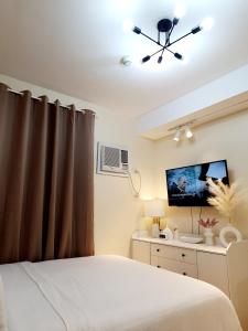 um quarto com uma cama e uma televisão de ecrã plano em Serenity Condo: Your Cozy Place At Stanford Suites 2 w/ Private Parking em Silang