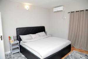 sypialnia z białym łóżkiem z czarnym zagłówkiem w obiekcie AJ HOMES w mieście Benin