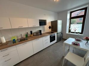 a kitchen with white cabinets and a table and a window at Premium Unterkunft für Monteure und Geschäftsreisende : Vollausgestattet, WIFI & Washing in Lembruch