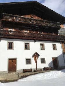 Biały dom z drewnianym dachem w śniegu w obiekcie Planerhof 
