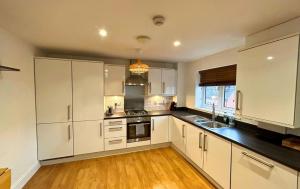 a kitchen with white cabinets and a black counter top at Wokingham Spectacular 2 Bedroom Penthouse in Bracknell