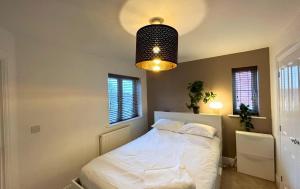 a bedroom with a white bed and a pendant light at Wokingham Spectacular 2 Bedroom Penthouse in Bracknell