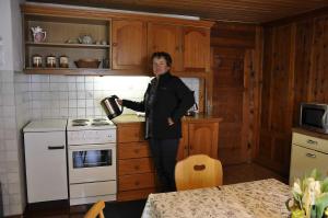 a woman standing in a kitchen holding a pot at Schweizerhof 