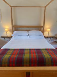 a bed with a striped blanket and two lamps on tables at The Gordon Arms Restaurant with Rooms in Yarrow