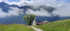 uma pequena igreja numa colina com montanhas ao fundo em Haus Lukasser em Assling