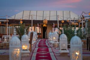 a pathway with white chairs and lights in front of a building at Sahara Luxury Camp in Merzouga