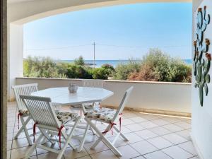 een tafel en stoelen op een balkon met uitzicht op de oceaan bij Casa Dansodà in Torre Lapillo