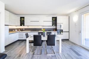 een keuken met witte kasten en een tafel en stoelen bij casa serena e alice in Lenno
