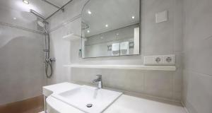 ein weißes Badezimmer mit einem Waschbecken und einem Spiegel in der Unterkunft PLAZA INN Rieker Stuttgart Hauptbahnhof in Stuttgart