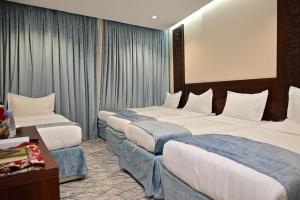 a hotel room with three beds and a table at فندق أورنسيس الحرم in Mecca