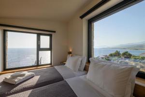 a bedroom with a bed with a large window at Mani Suites luxury seaside accommodation in Agios Nikolaos