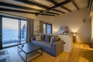 a living room with a couch and a large window at Mani Suites luxury seaside accommodation in Agios Nikolaos