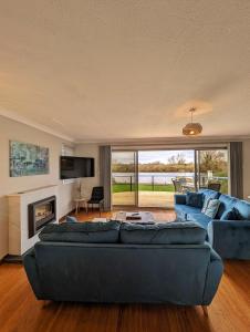 a living room with two blue couches and a fireplace at River View - Norfolk Broads in Brundall