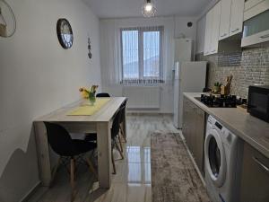 a kitchen with a table with chairs and a refrigerator at Tei Residence in Piatra Neamţ