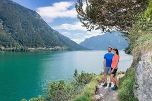 a man and woman standing on a path by a lake at Chalets Grossmitt in Pertisau