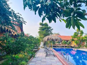 uma piscina num resort com bancos e árvores em Trang An Quynh Trang Happy Homestay & Garden em Ninh Binh