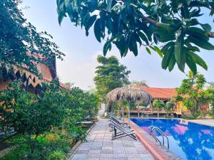 a pool at a resort with benches and trees at Trang An Quynh Trang Happy Homestay & Garden in Ninh Binh