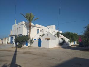 a white building with a blue door and a palm tree at Dar Janis Djerba دار يانيس جربة in Houmt Souk