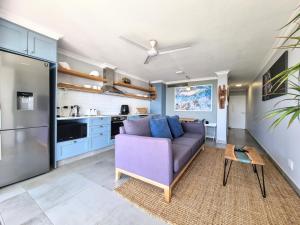 a living room with a purple couch and a kitchen at 77 Chaka's Cove in Ballito