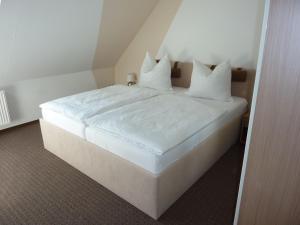 1 cama con sábanas blancas y almohadas en una habitación en Schöne Fewo max 4 Pers in der Nähe von Sassnitz, 