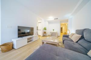 ein Wohnzimmer mit einem Sofa und einem TV in der Unterkunft HomeHolidaysRentals Zen - Costa Barcelona in Pineda de Mar