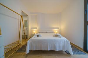 Schlafzimmer mit einem weißen Bett und einem Spiegel in der Unterkunft HomeHolidaysRentals Zen - Costa Barcelona in Pineda de Mar